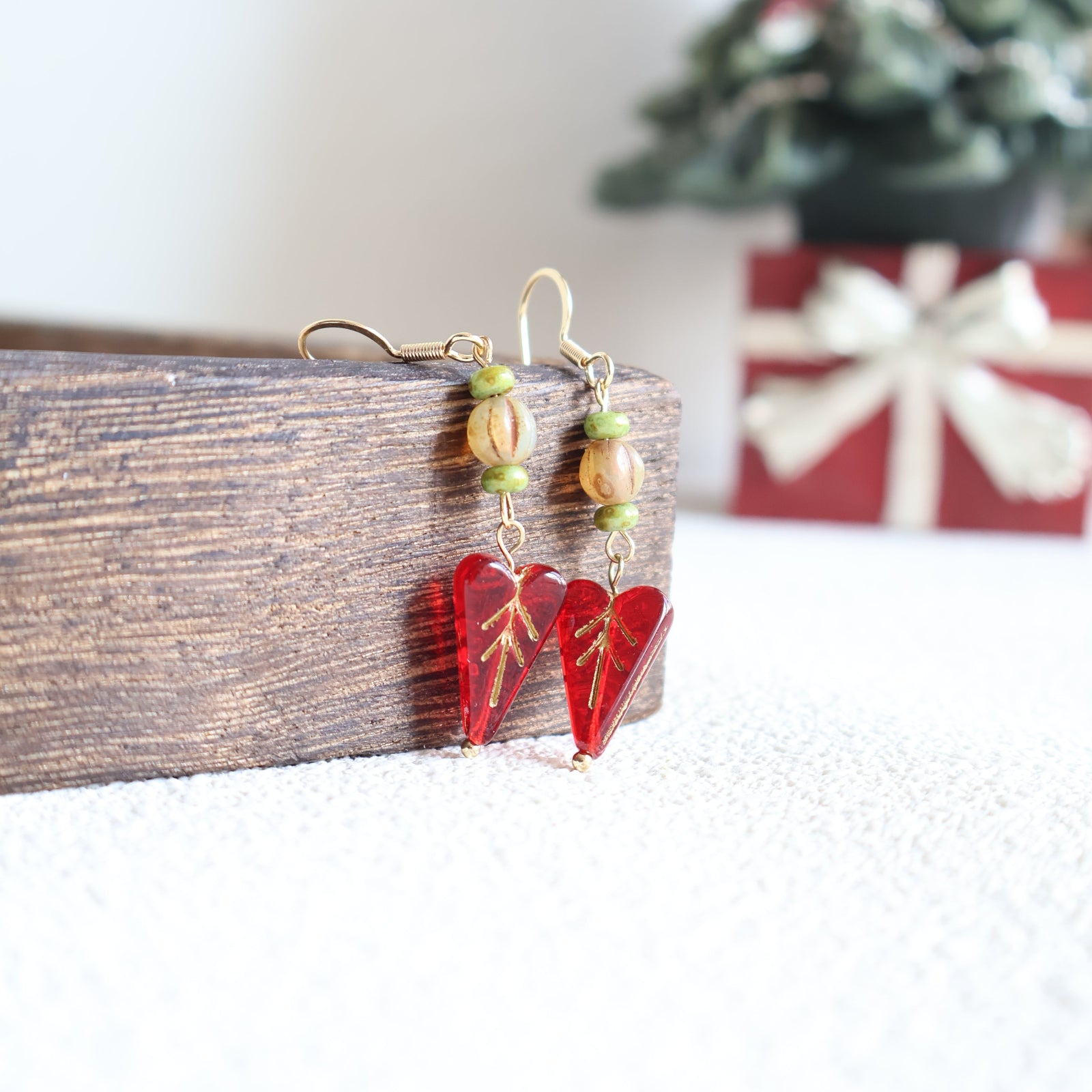 Earrings with red and green beads on a wooden surface
