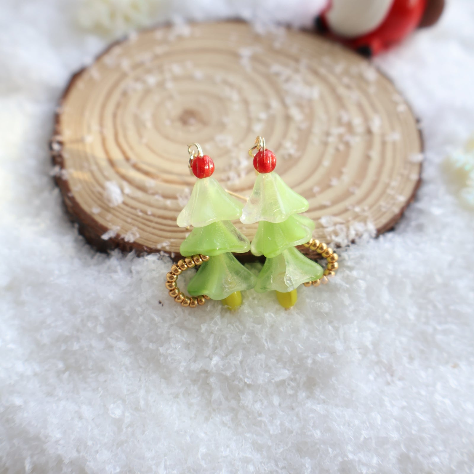 Decorative hair clip with green leaves and red berries on a wooden block with snow in the background