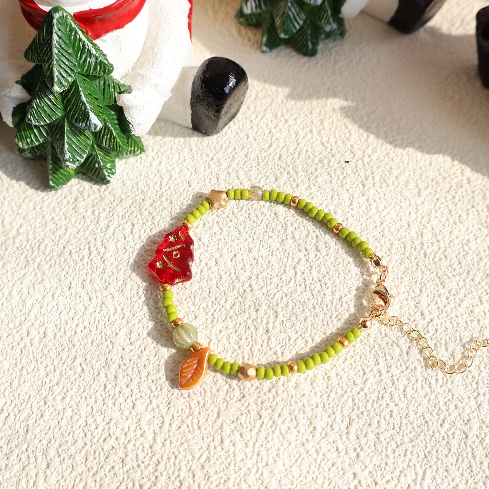 Bracelet with green beads and red and orange accents on a textured surface