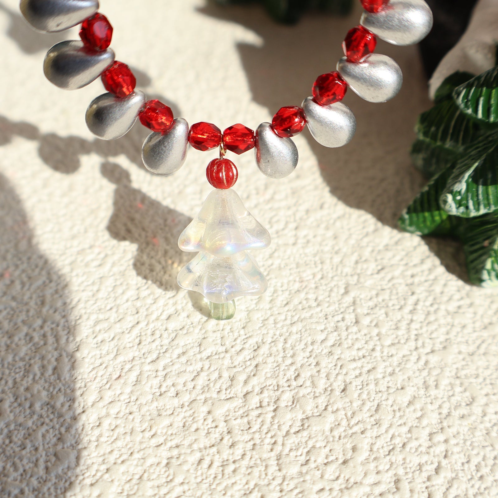 Necklace with red and silver beads on a textured surface
