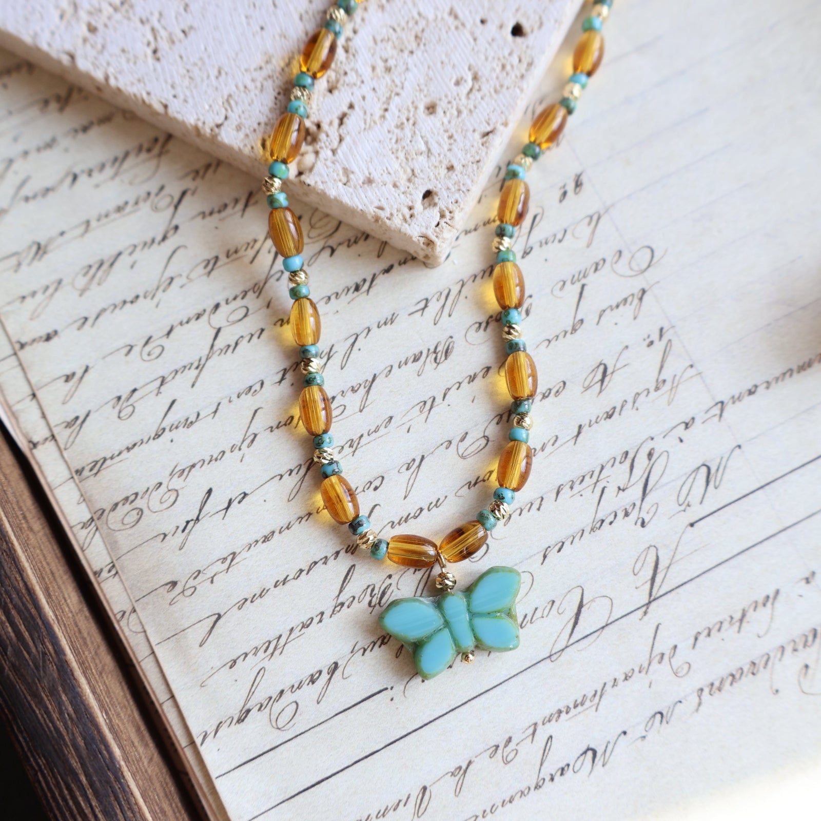 Beaded necklace with a butterfly charm on an old letter