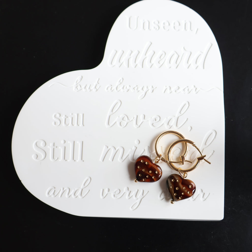 Heart-shaped earring display card with earrings on a black background