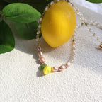 Bracelet with yellow beads and green leaves on a textured white surface