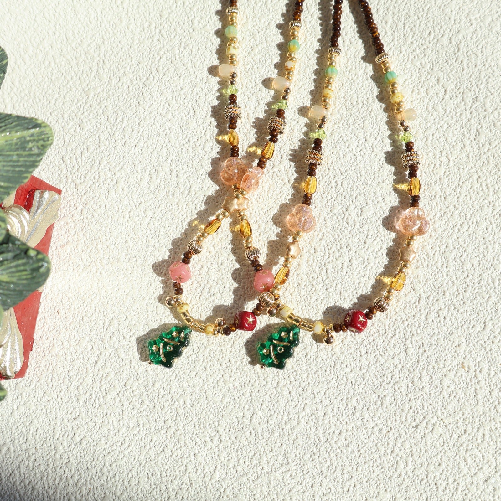 Beaded necklaces with floral pendants on a textured white surface