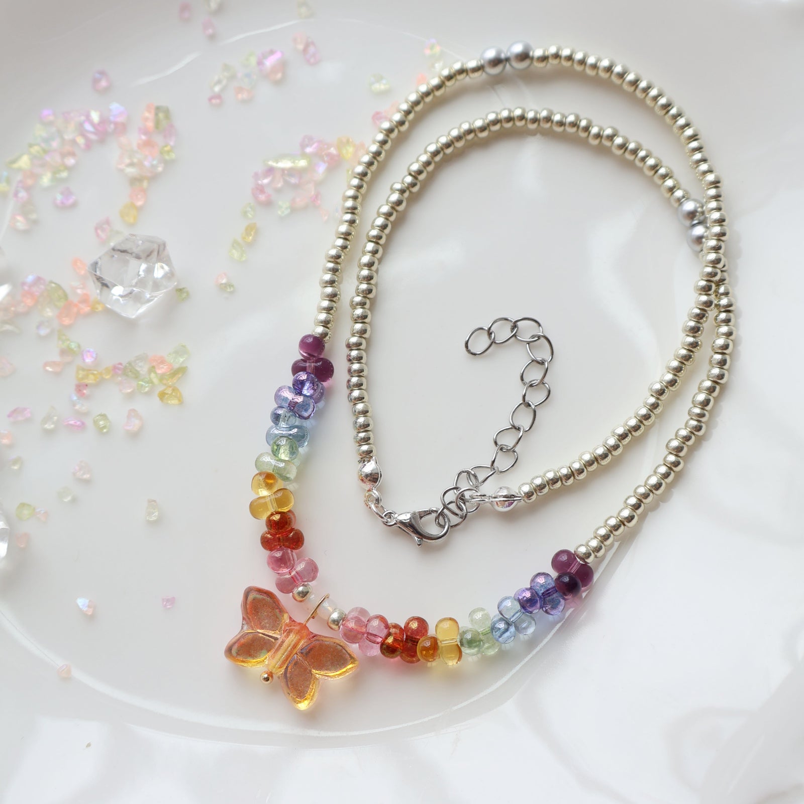 Necklace with colorful beads and a butterfly charm on a white background