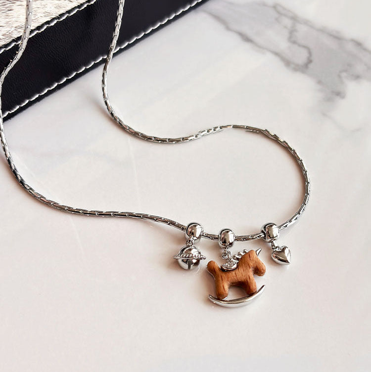 Necklace with a wooden horse pendant on a marble surface
