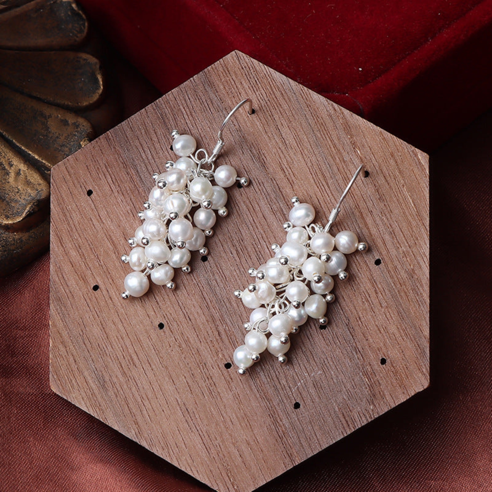 Pearl earrings on a wooden stand with a dark background