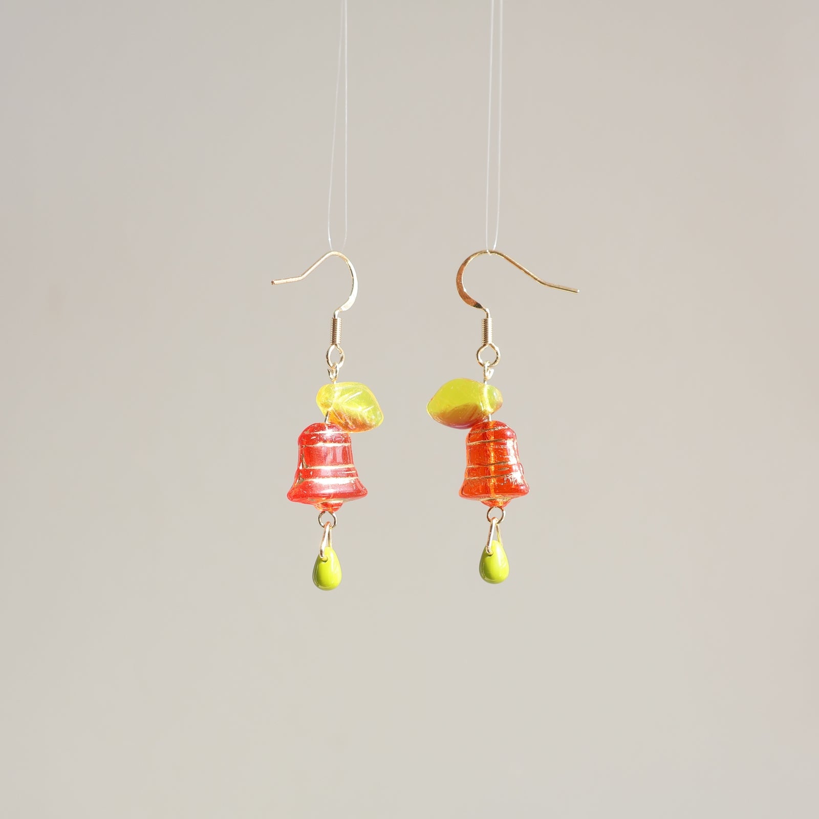 Pair of colorful bell-shaped earrings on a plain background