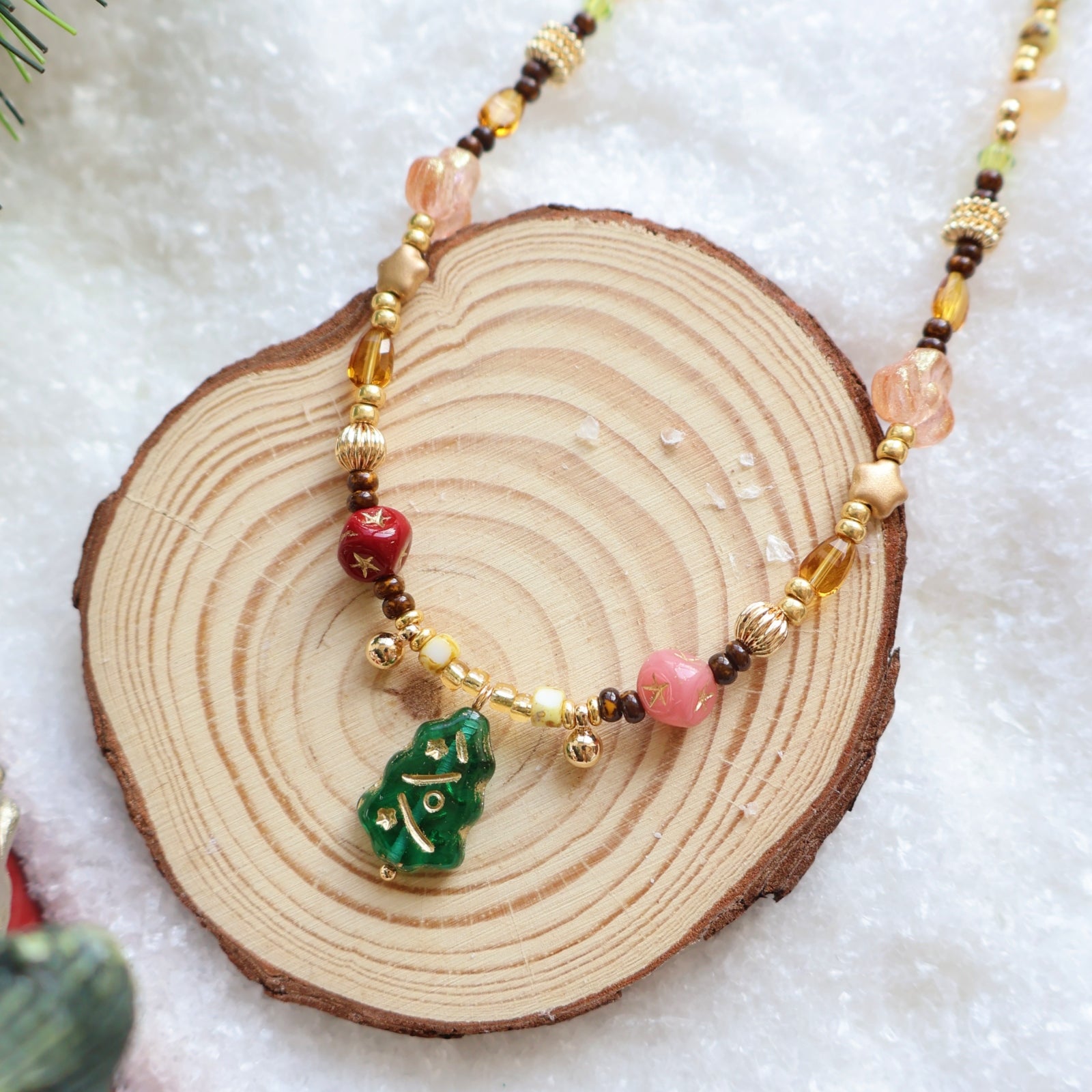 Beaded necklace with a green leaf pendant on a wooden slice