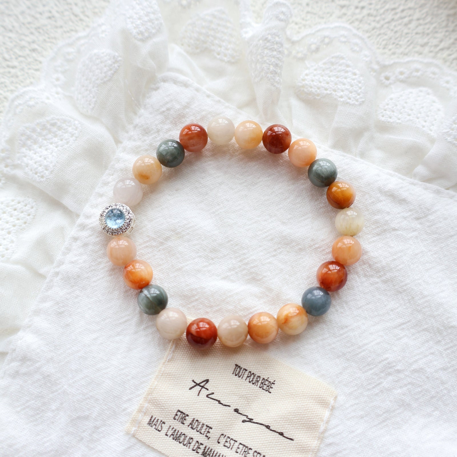 Multicolored beaded bracelet with a charm on a textured white surface