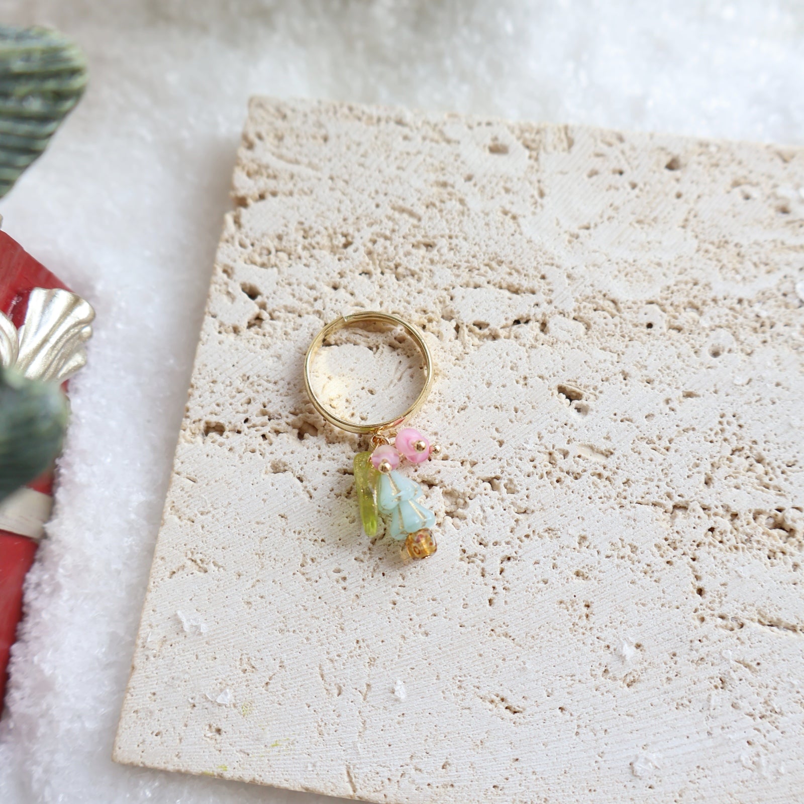 Gold ring with colorful charms on a textured stone surface