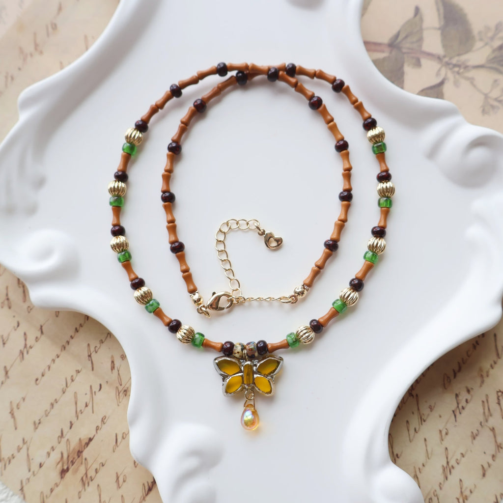 Beaded necklace with a butterfly pendant on a decorative white plate.