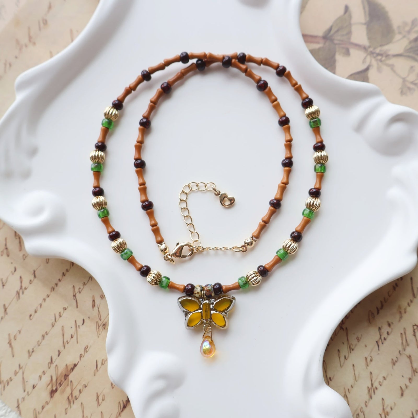Beaded necklace with a butterfly pendant on a decorative white plate.