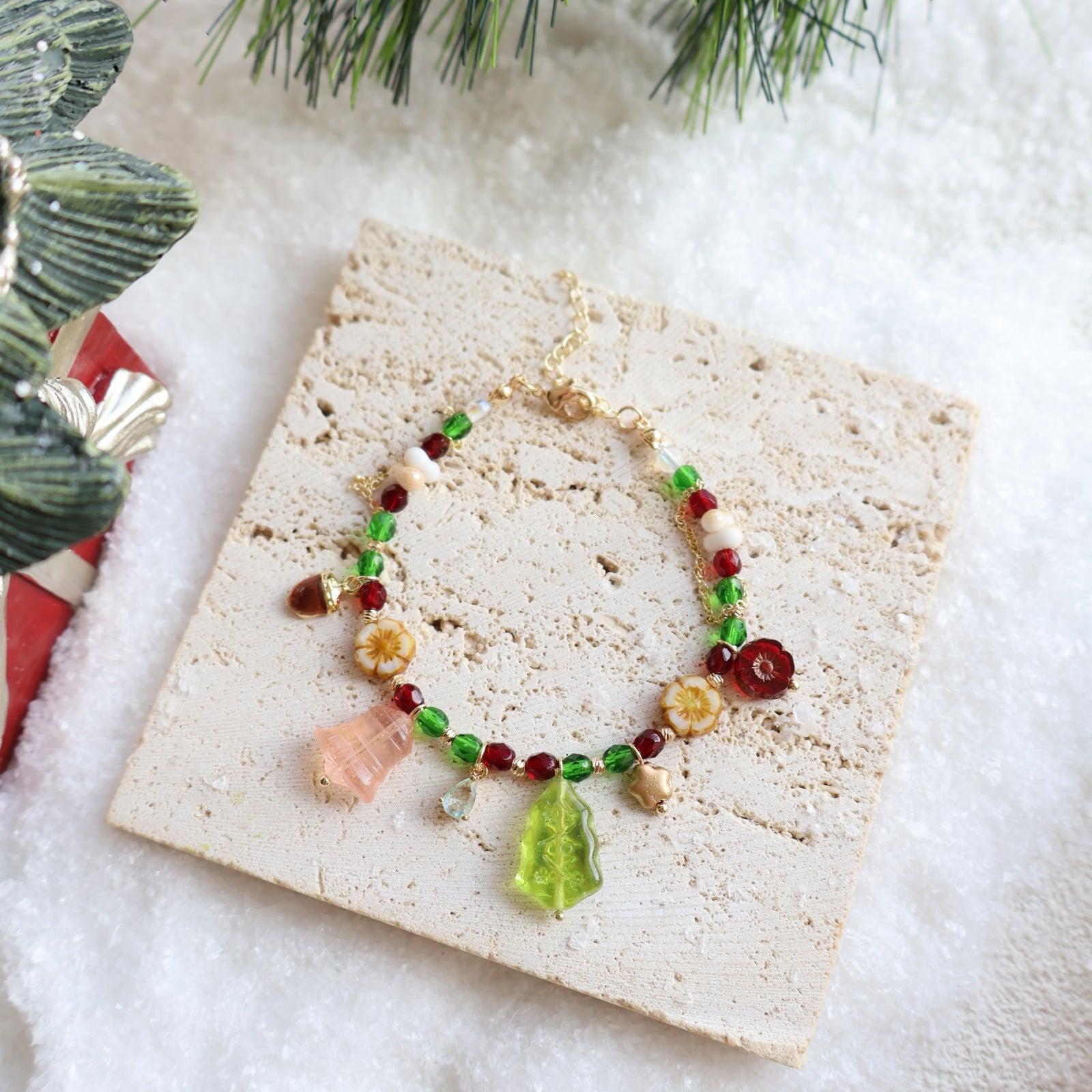 Necklace with colorful beads on a stone surface with a Christmas-themed decoration in the background.