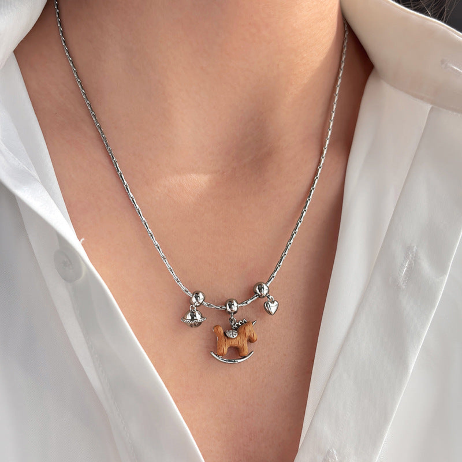 Necklace with a horse pendant on a person wearing a white shirt