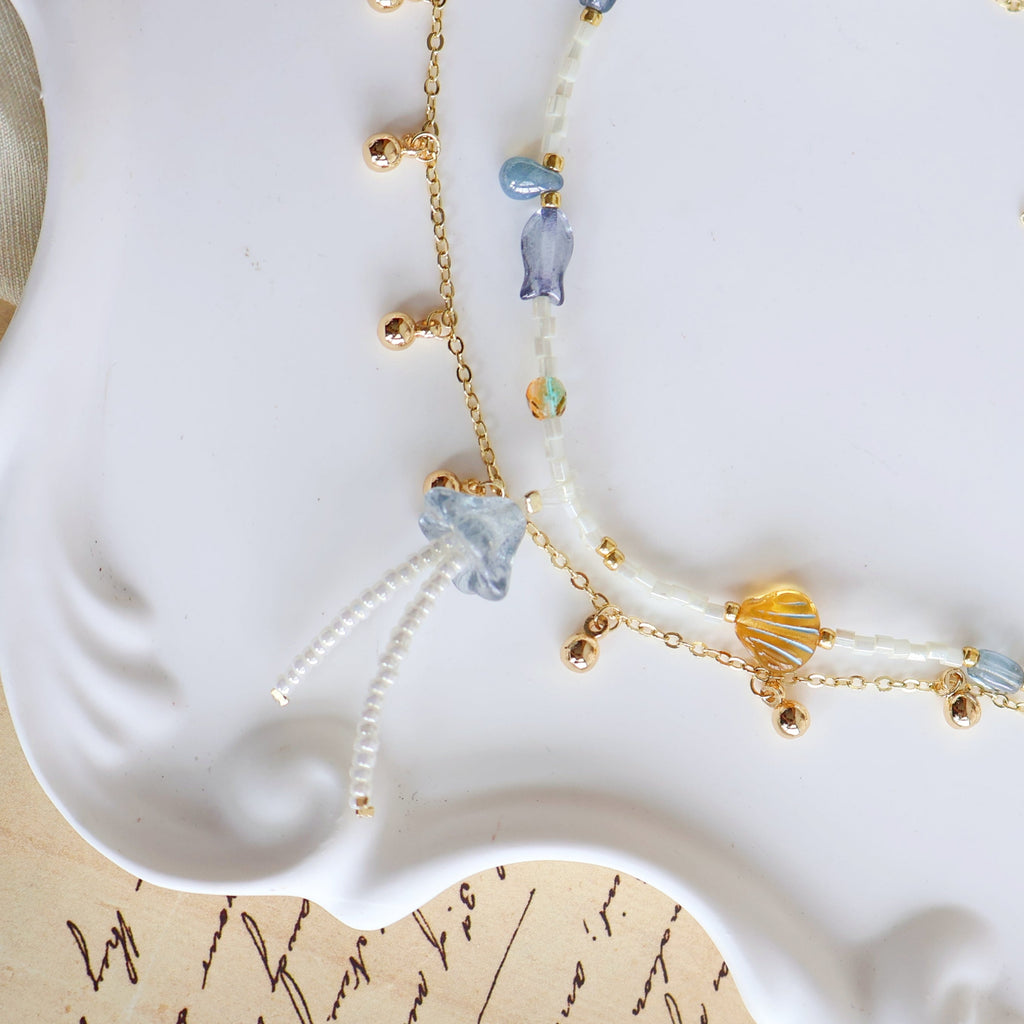 Delicate necklace with blue and gold beads on a white dish