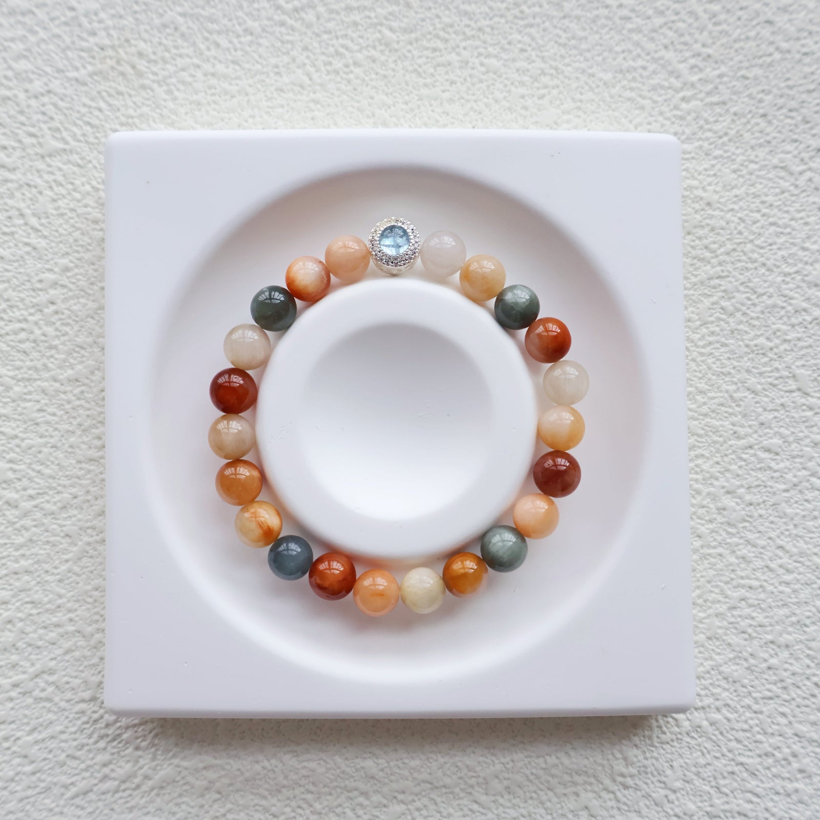 Multicolored beaded bracelet on a white dish with a white background