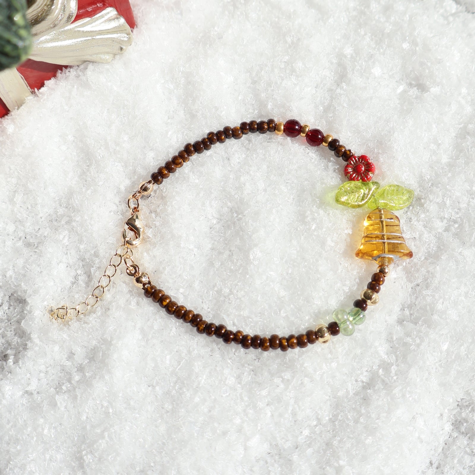 Beaded bracelet with a bell charm on a white textured surface