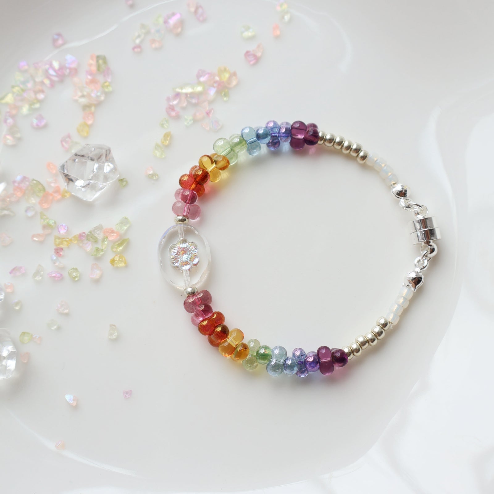 Multicolored beaded bracelet on a white plate with decorative crystals.