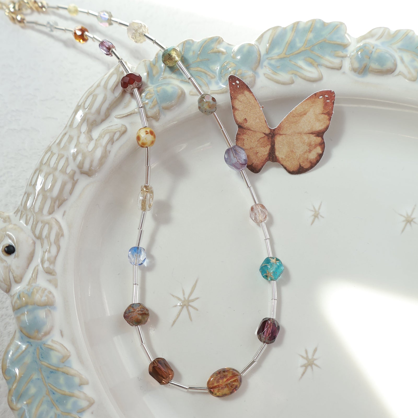 Beaded necklace with a butterfly charm on a decorative plate