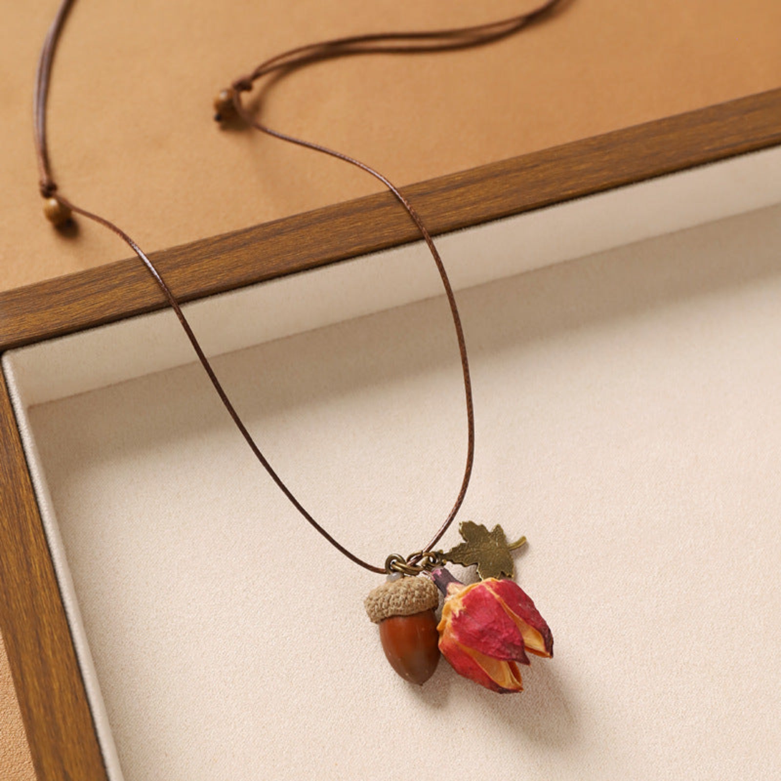 Necklace with acorn and leaf pendant on a wooden surface