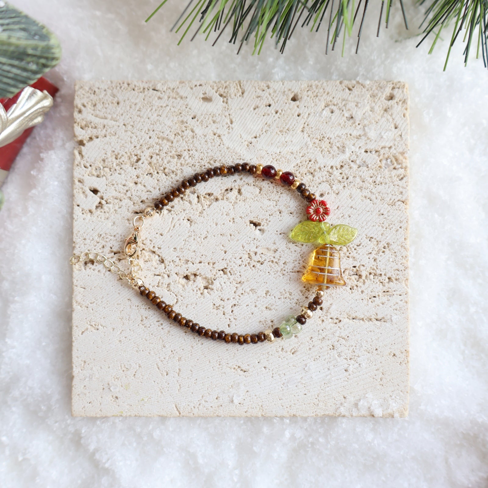Bracelet with decorative elements on a textured surface with Christmas decorations.