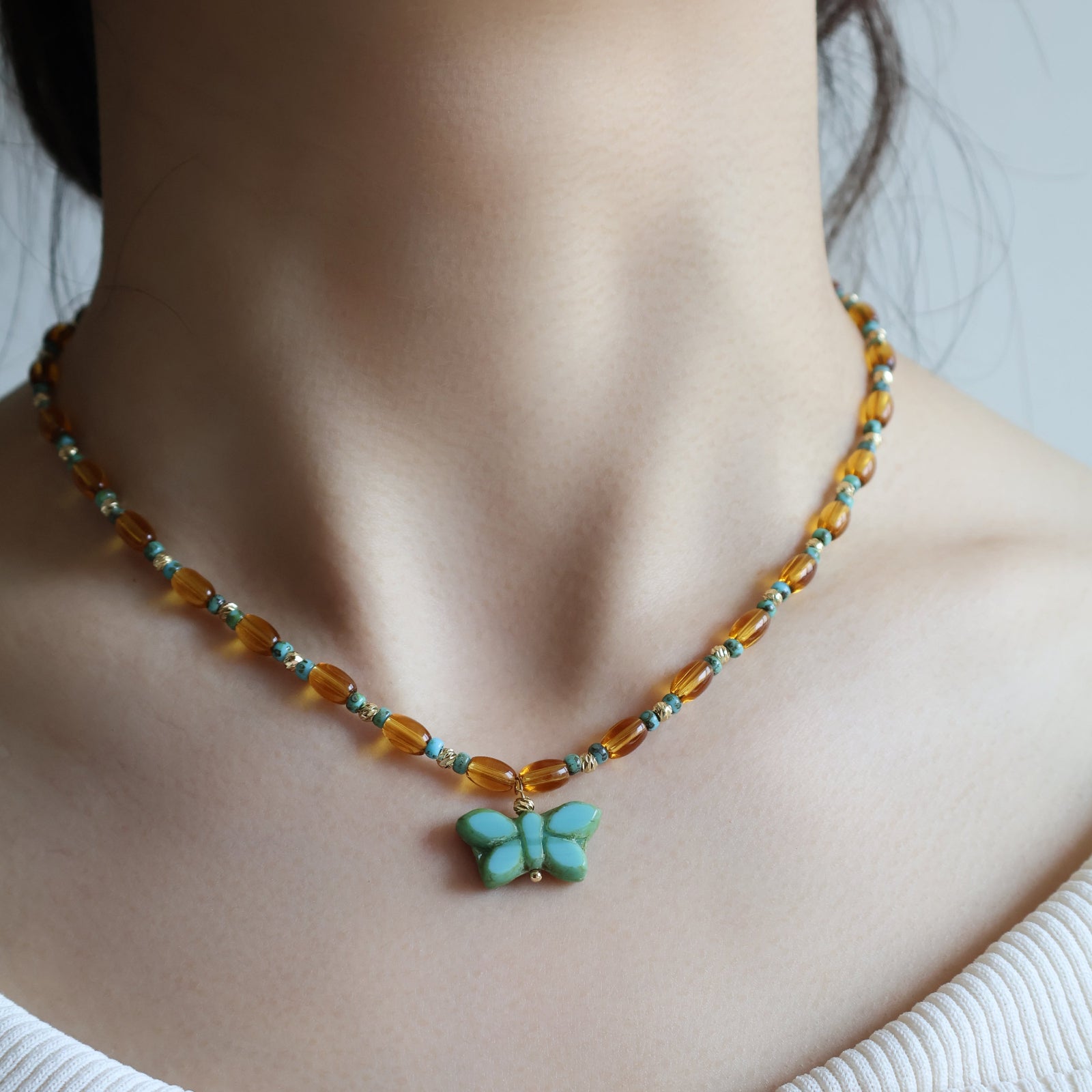 Necklace with a butterfly pendant worn by a person