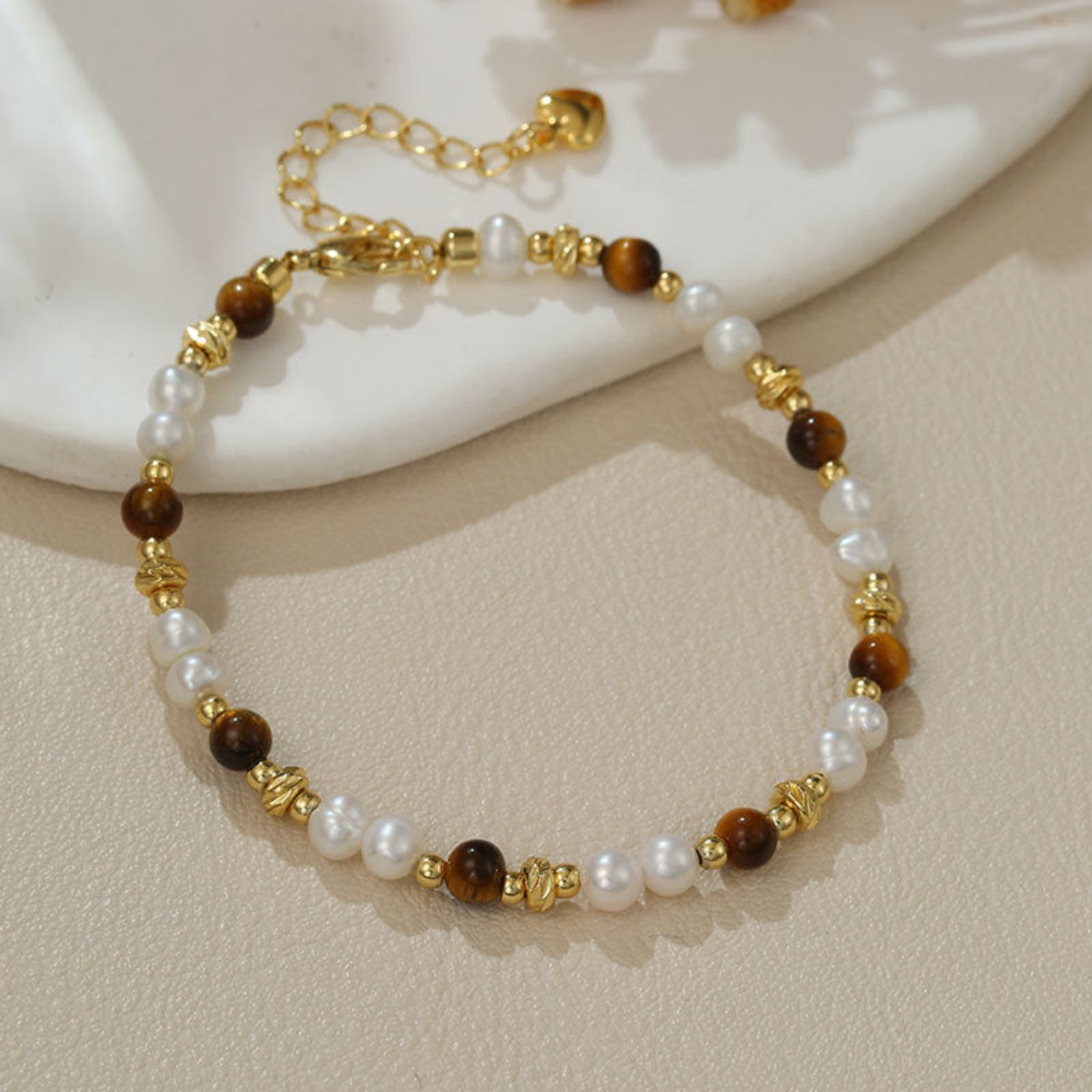 Bracelet with pearls, brown beads, and gold accents on a beige surface