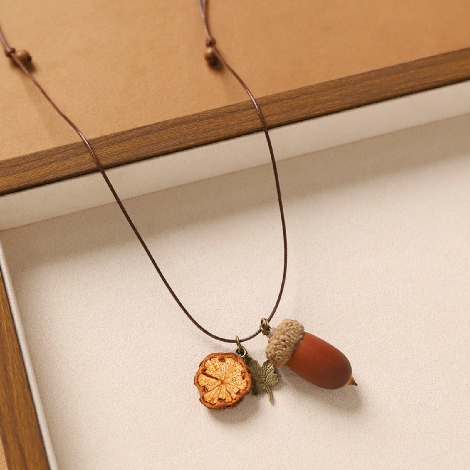 Necklace with acorn and leaf pendant on a wooden surface