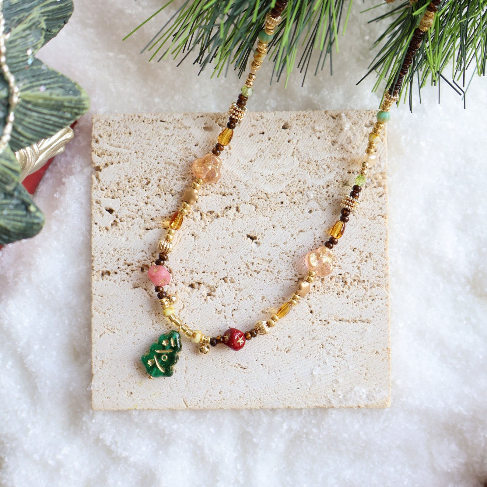 Beaded necklace on a decorative card with Christmas tree branches in the background
