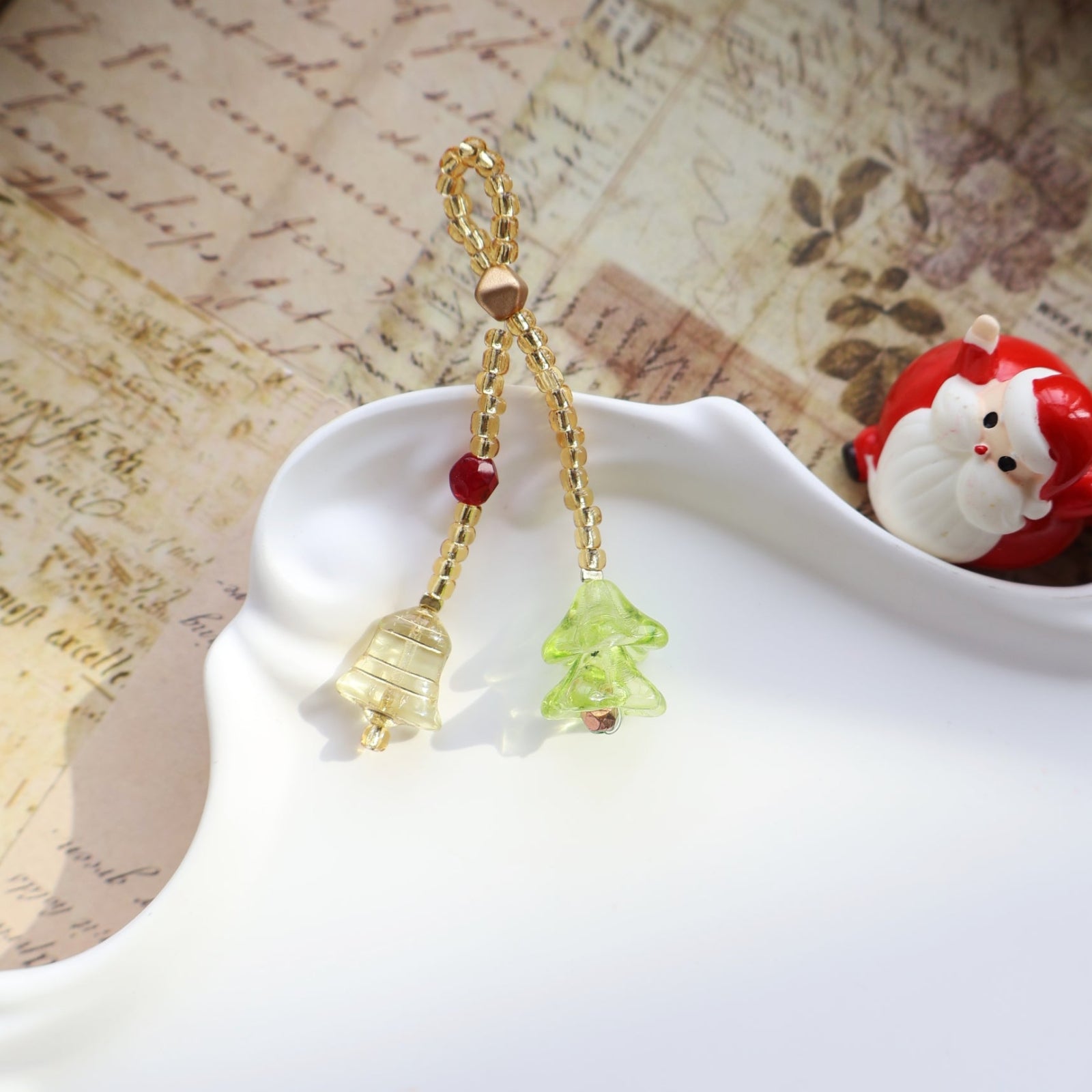 Decorative keychain with gold chain, red and green pendants on a textured surface