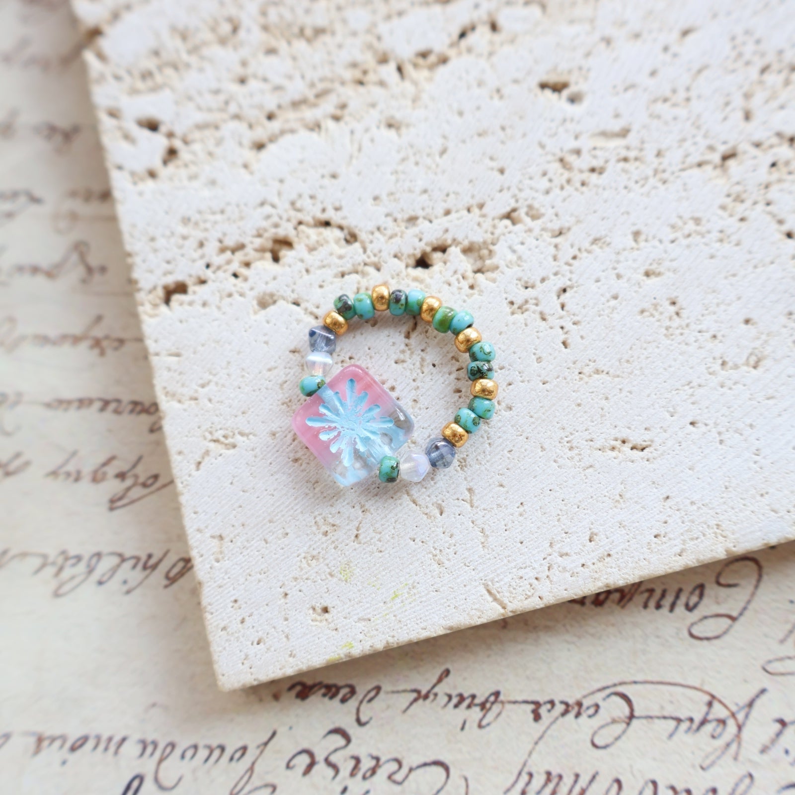 Small ring with a colorful stone on a textured surface