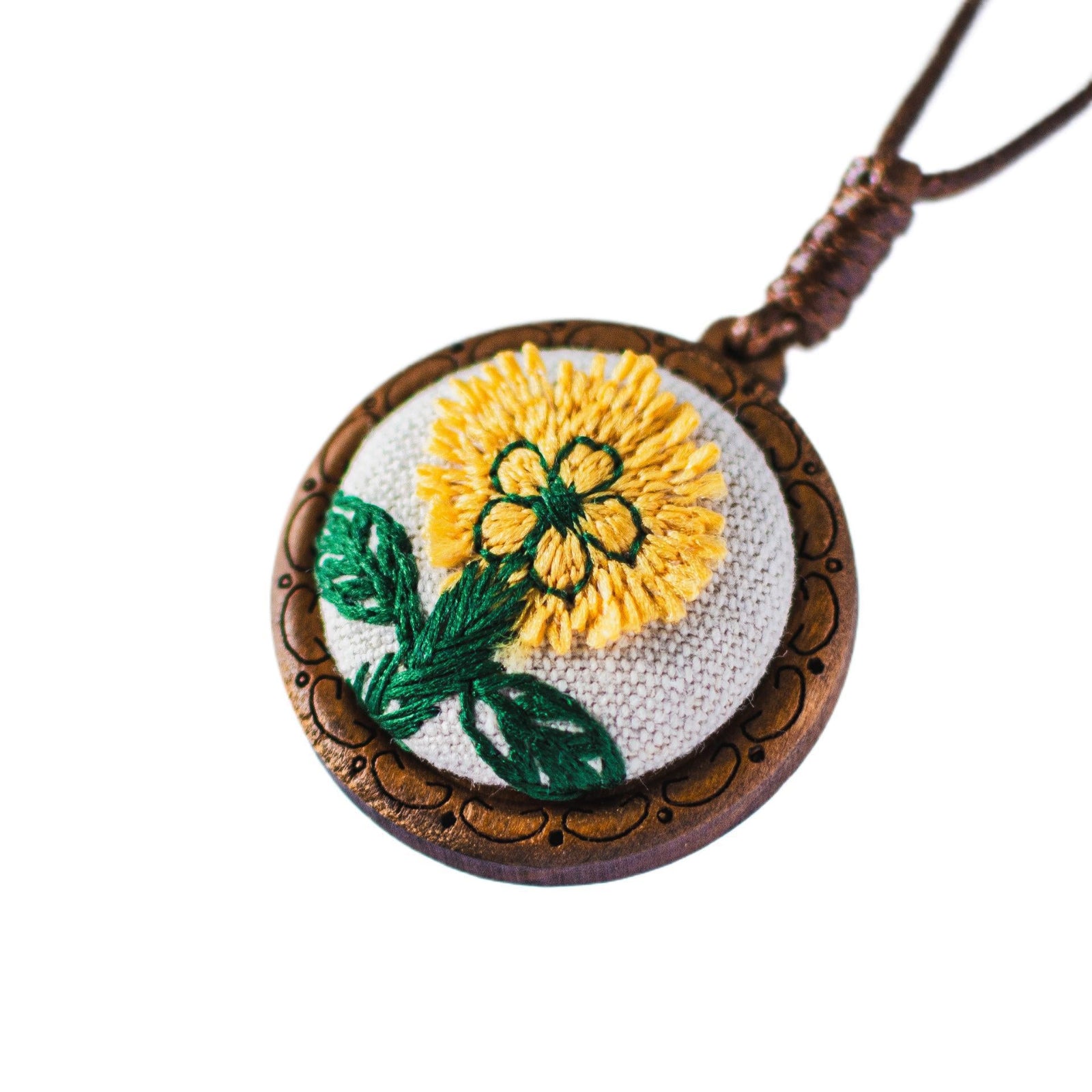 Embroidered pendant with yellow flower and green leaves on a white background
