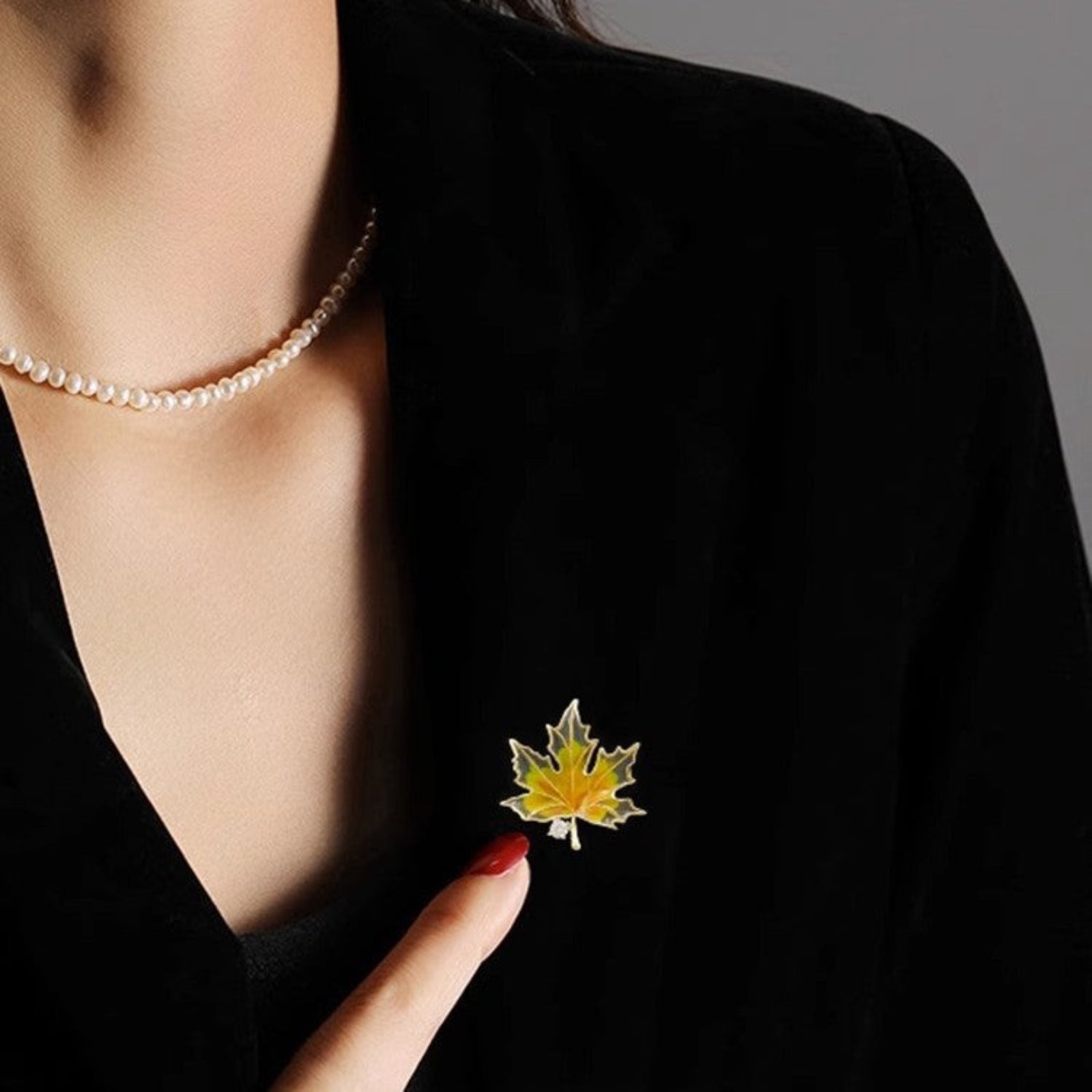 Person wearing a black blazer with a yellow maple leaf brooch.