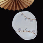 Star-shaped jewelry on a white stone surface with a gold fan in the background