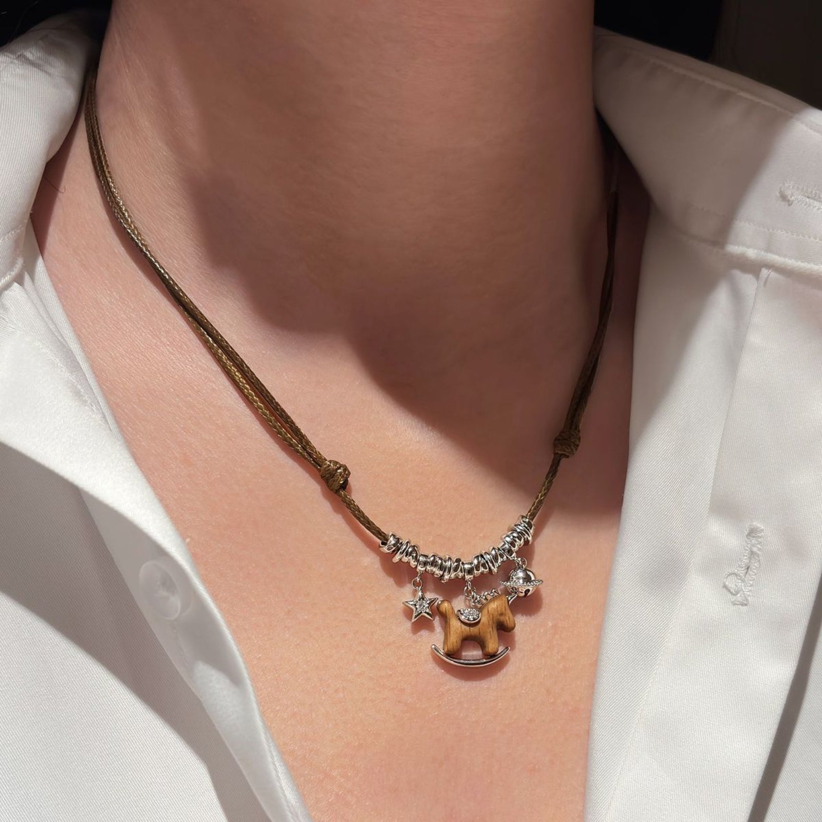 Necklace with a horse charm worn by a person in a white shirt
