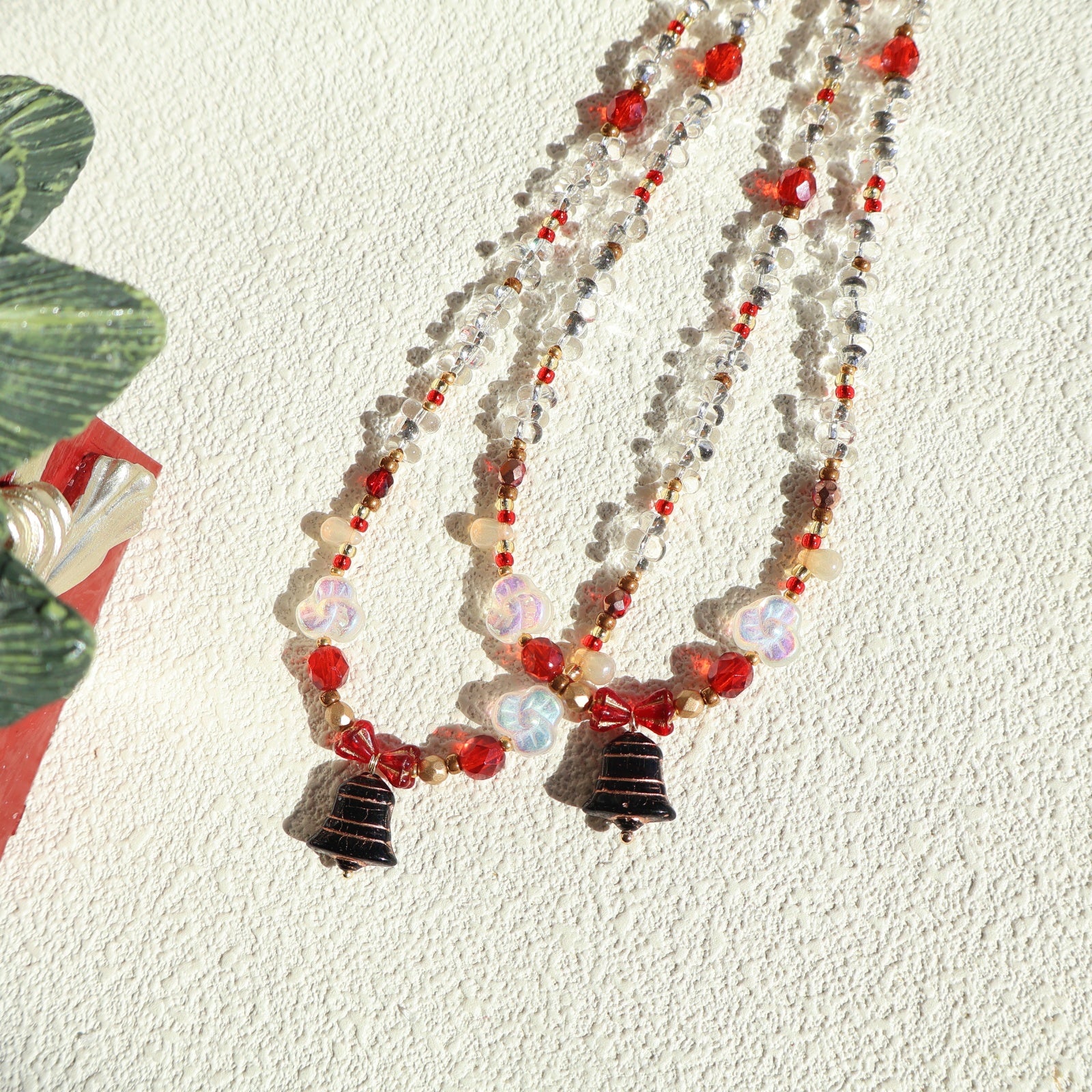 Beaded necklace with red and black accents on a textured white surface