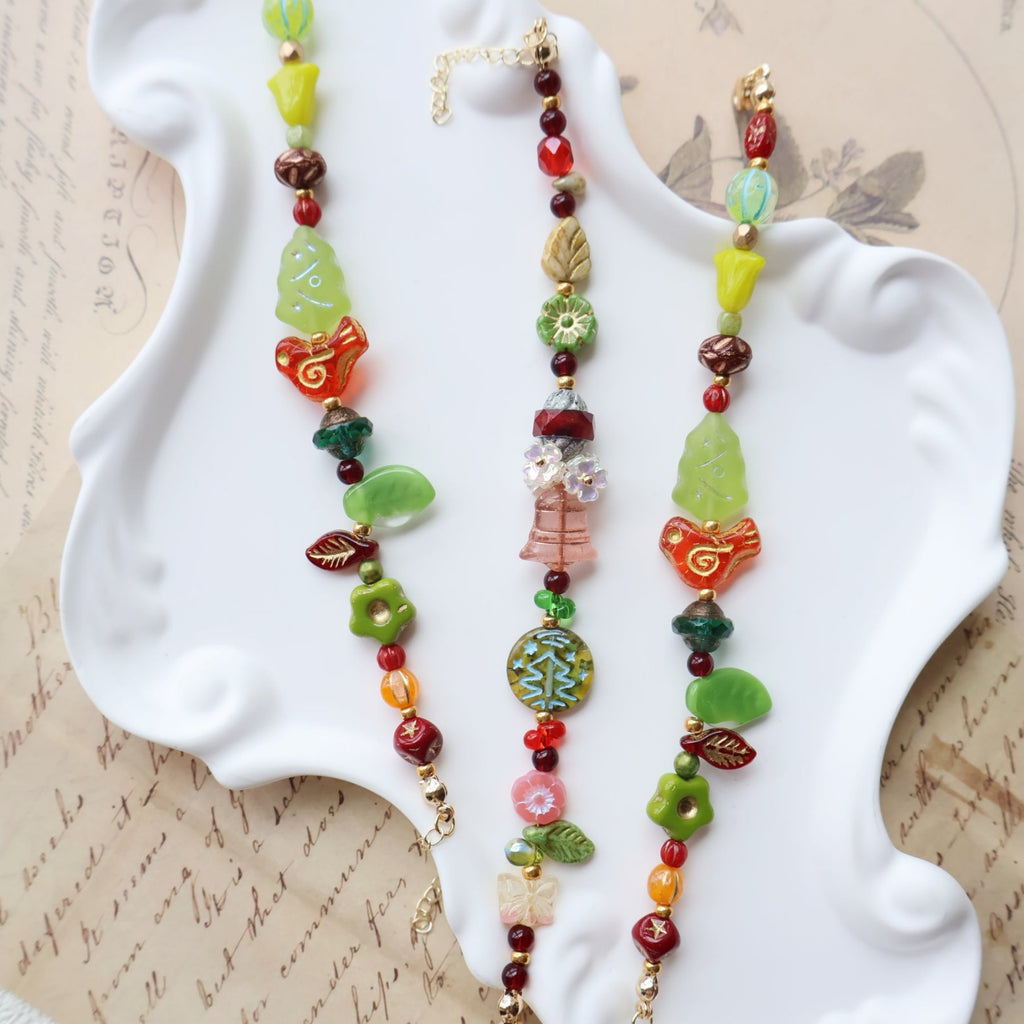 Colorful beaded necklaces on a white dish with an old letter background