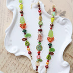Colorful beaded necklaces on a white dish with an old letter background